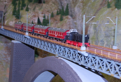 Modellbahn fährt über eine Brücke