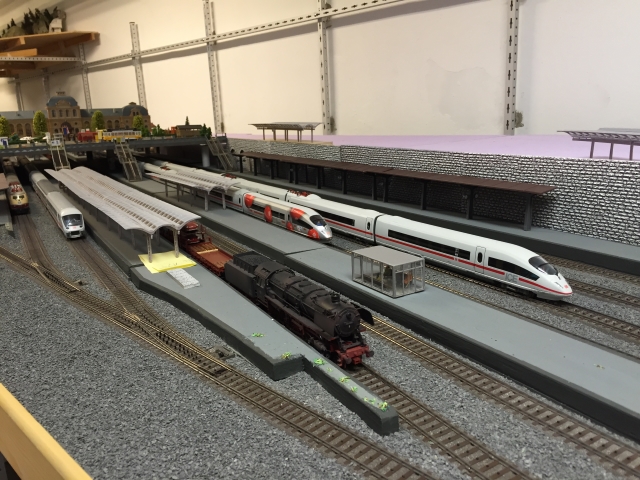 Schöfferstadt Hauptbahnhof - Bahnhofsausfahrt mit verschiedenen Zügen an den Bahnsteigen