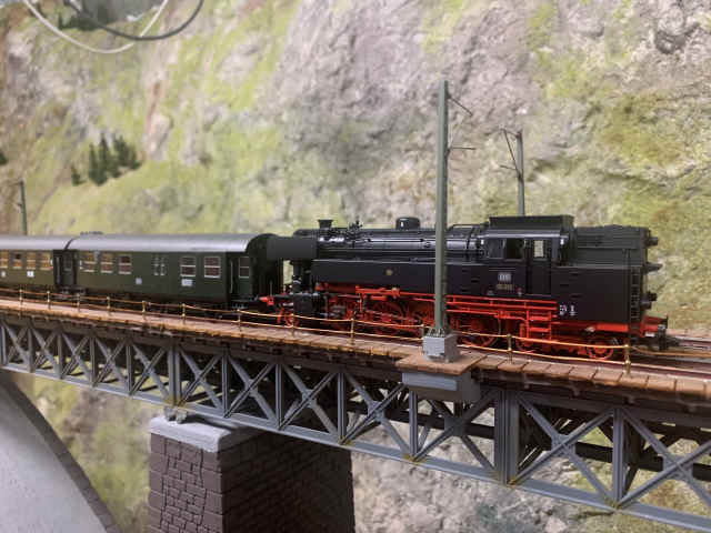 Dampflokomotive der Baureihe 65 fährt mit Personenanhängern über die Brücke der Paradestrecke