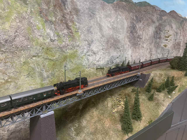 Zwei Züge mit Dampflokomotiven begegnen sich auf der Brücke